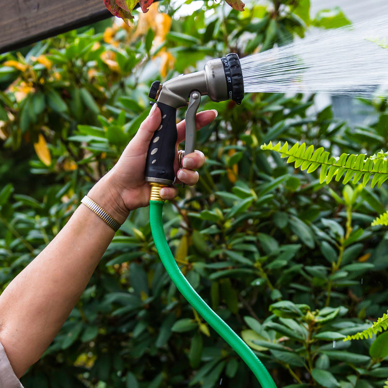 Woman spraying water from a green hose