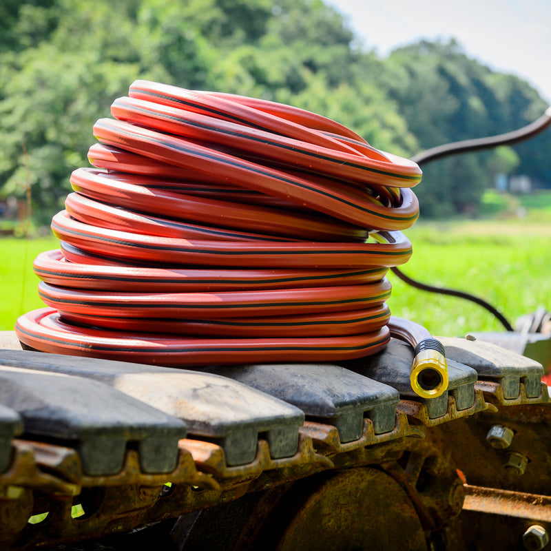 A red hose wrapped up and sitting on farm equipment