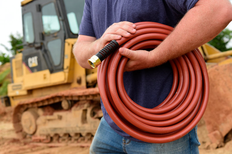 Man holding a red hose on a construction site