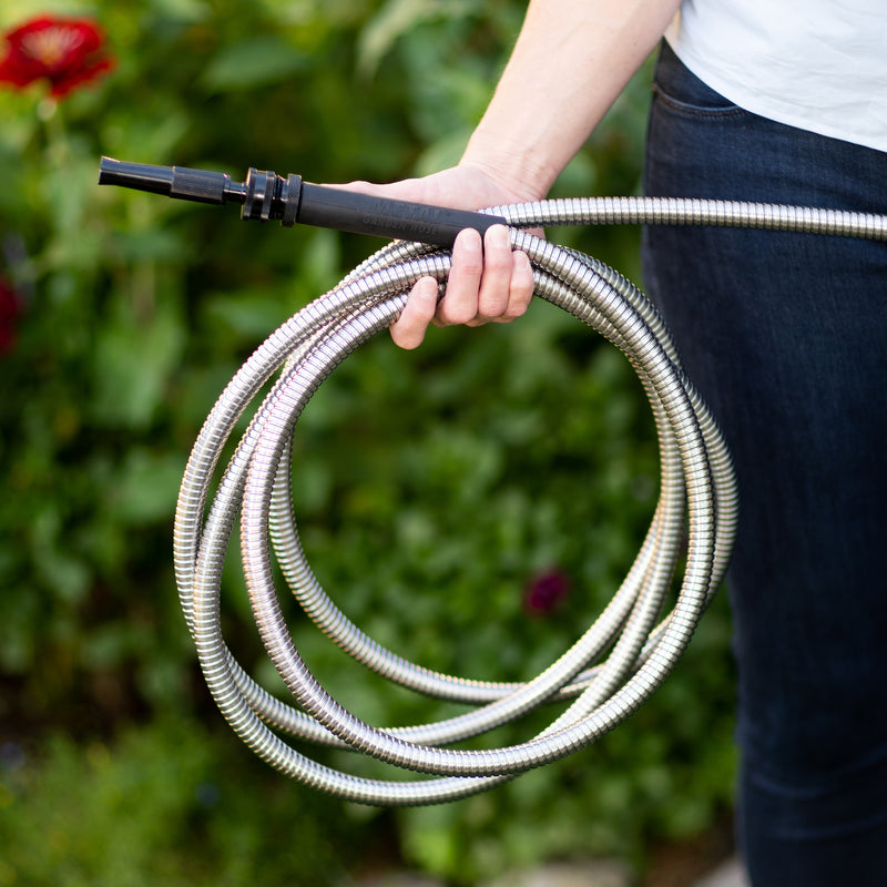 Person holding a metal garden hose in their hand