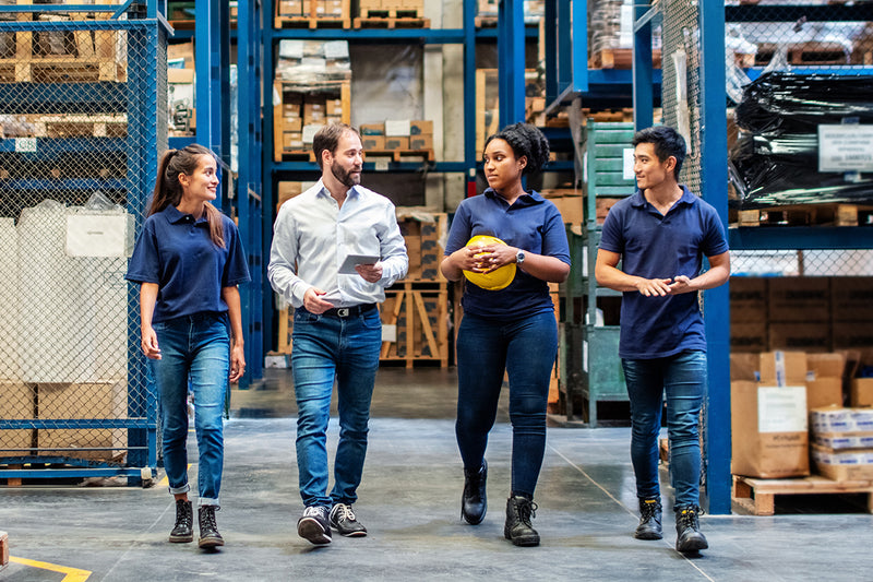 Four workers walking through a warehouse