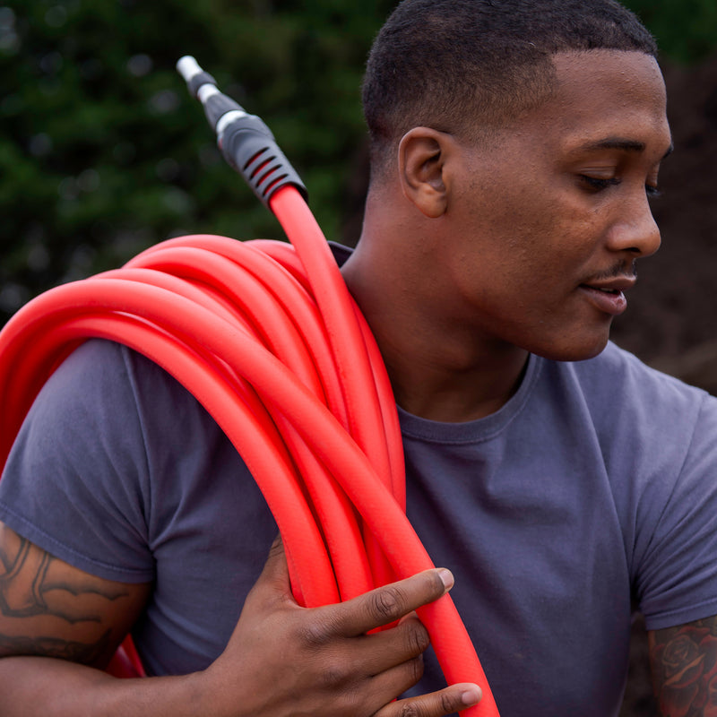 A man carrying a red hose over his shoulder