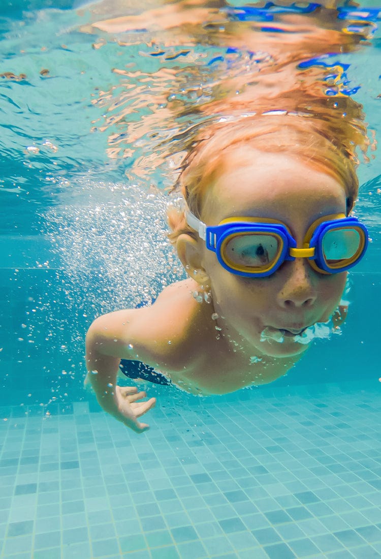 Child wearing goggles while swimming underwater