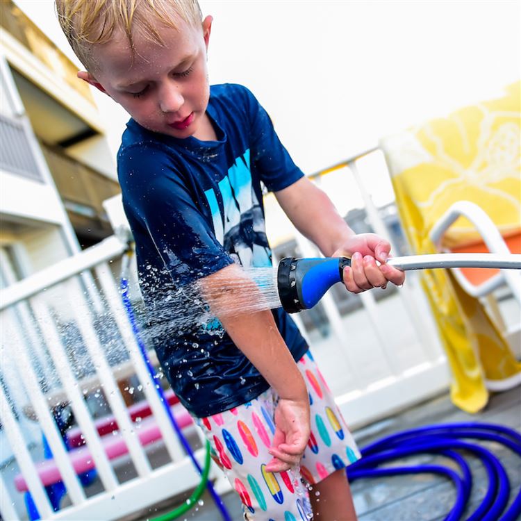 A child hosing himself off with the Swan 18" 9-Pattern Watering Wand