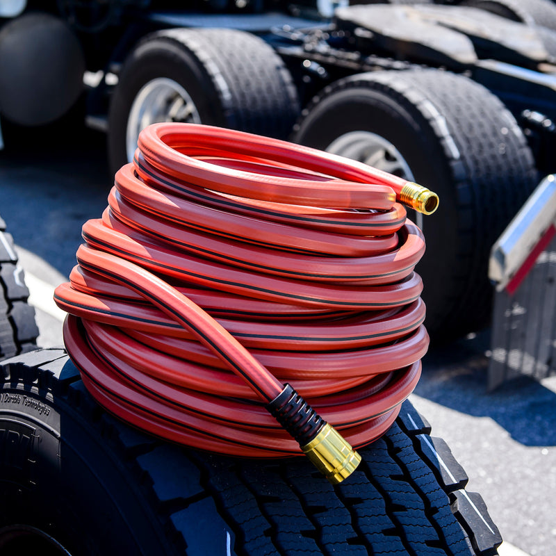 A red hose wrapped up and sitting on a tire