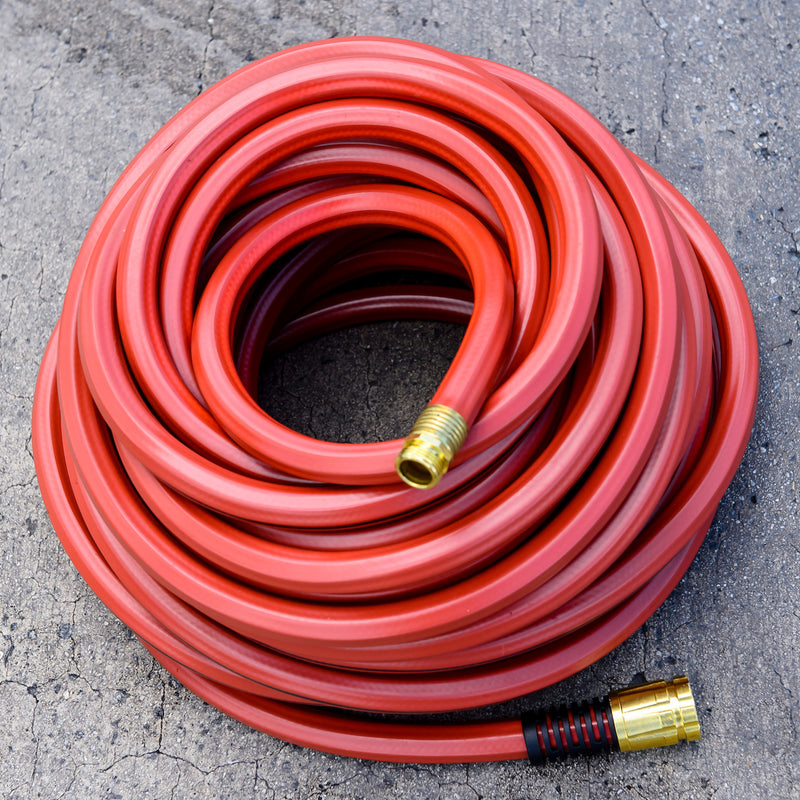 A red hose wrapped up and sitting on concrete