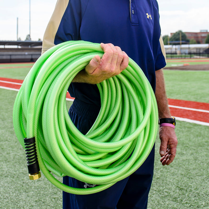 A man holding a light green hose wrapped around his forearm