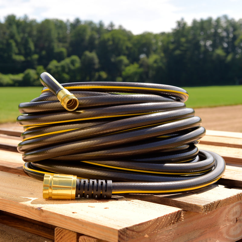 A black and yellow hose wrapped up on a wooden pallet