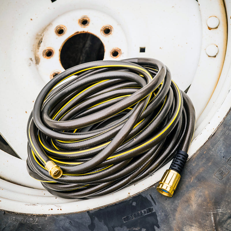 A black and yellow hose wrapped up and sitting on a large tire