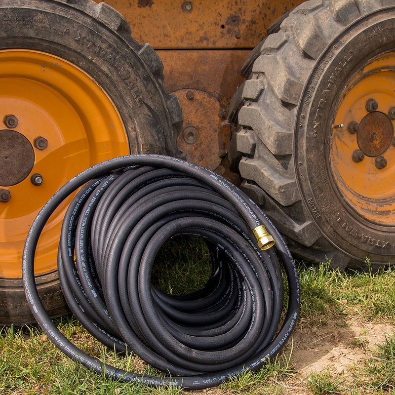 A black hose leaning against tractor tires