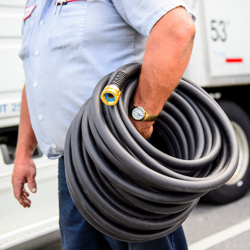 A man carrying a large black hose around his hand