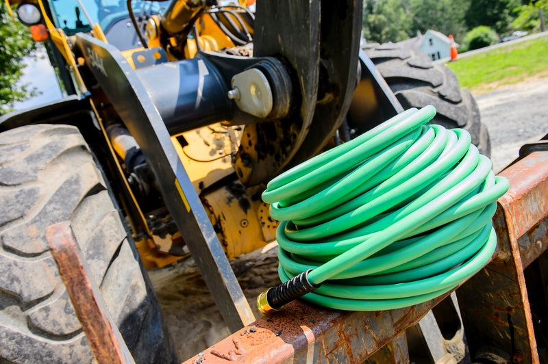 A coiled up green hose on construction equipment