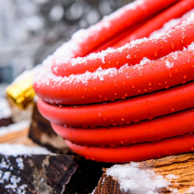 Close up of a coiled up red hose with snow on it