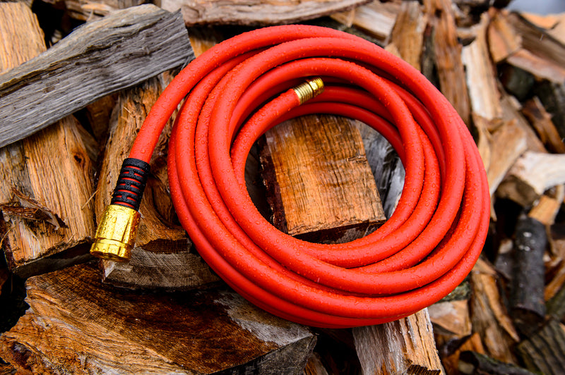 Red hose coiled up and sitting on top of chopped wood