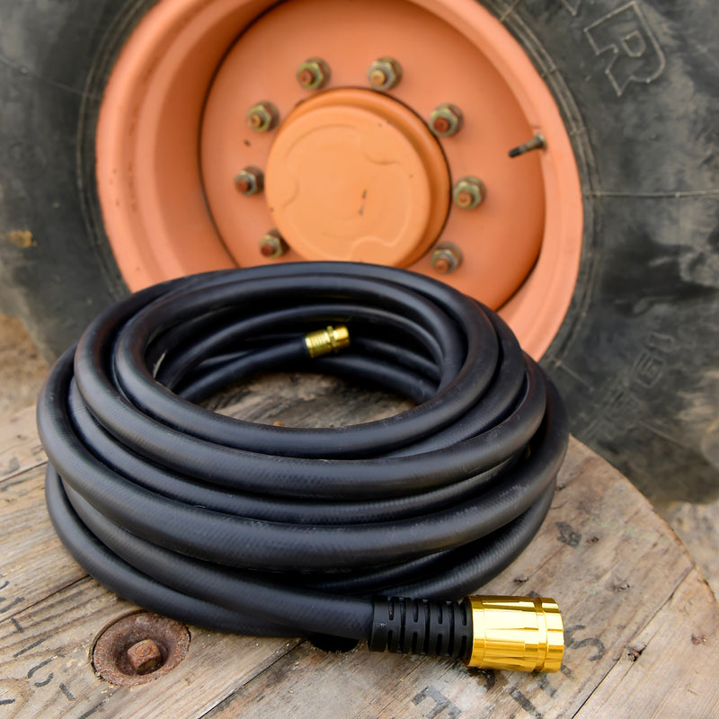 Coiled up black rubber hose beside a tractor tire