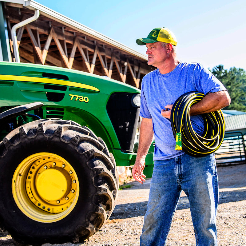 Man holding a rubber hose near a tractor